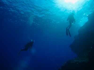 Underwater man dressed in a black wet clothes
